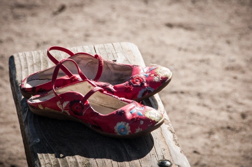 woman-sandals-on-bench-sunset.webp