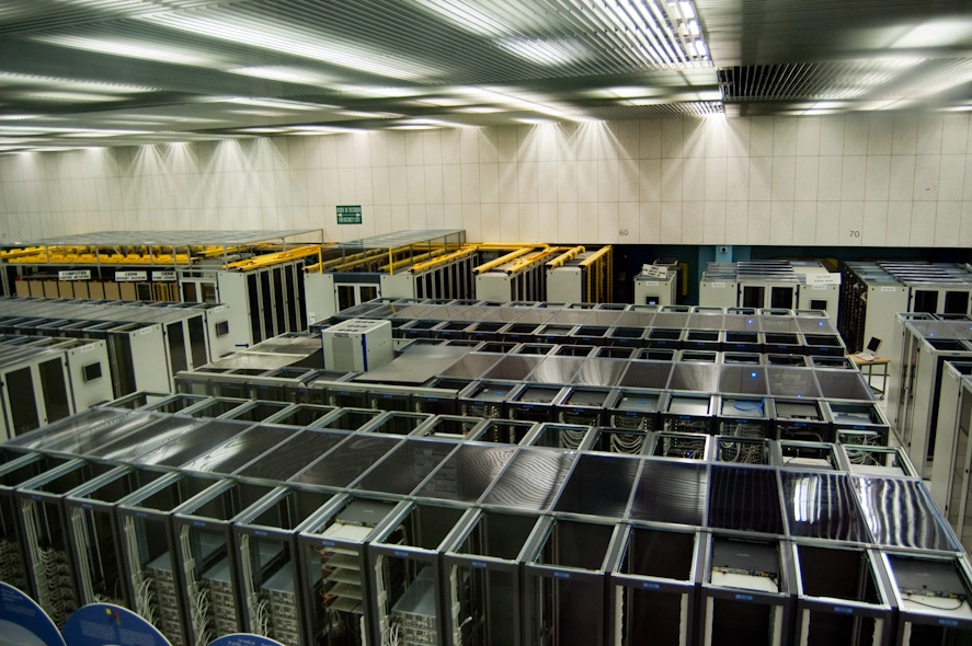 Desde mi ventana no veo montañas, veo lo que muestra la imagen: el centro de datos del CERN. Es un poco ruidoso, algo así como viajar en un avión, pero nada que unos cascos insonorizadores no puedan evitar. Dado que los ordenadores de un centro de datos tienen que estar fresquitos no es común sentir súbitas bocanadas de aire frío al pasar cerca de alguna de las puertas que dan a su interior. El edificio 513 es uno de los edificios ruidosos del CERN. Toda la ristra de ventiladores de hace dos fotos, necesarios para mantener fresquitos los ordenadores del centro de datos, hacen un ruido del demonio.